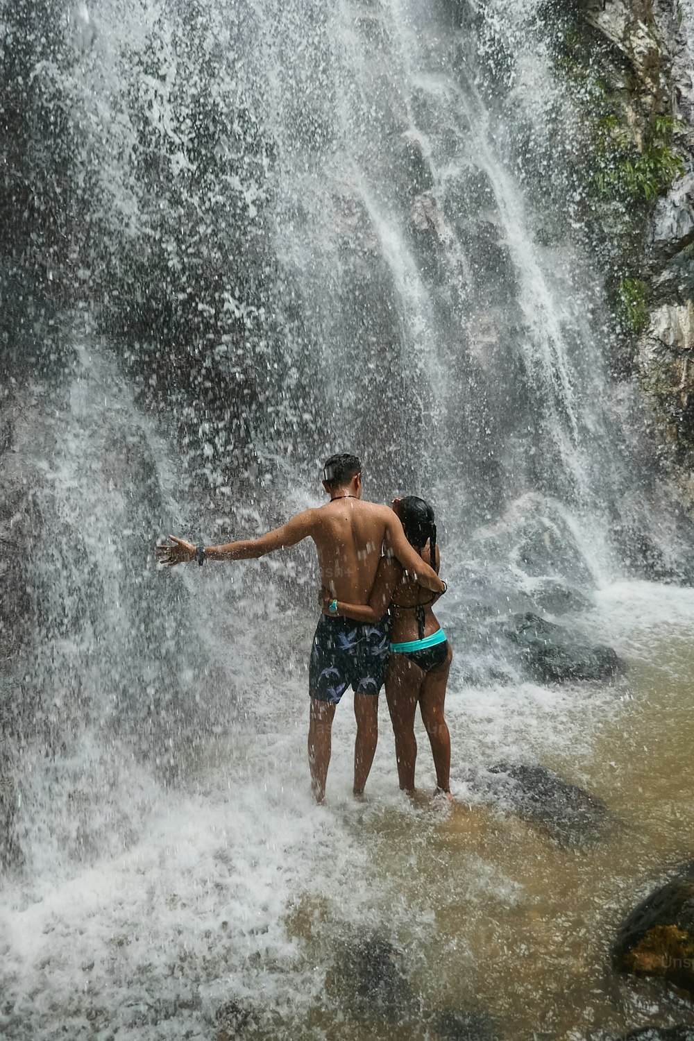 Boyfriends under waterfall, on the bottom of rocks and river.