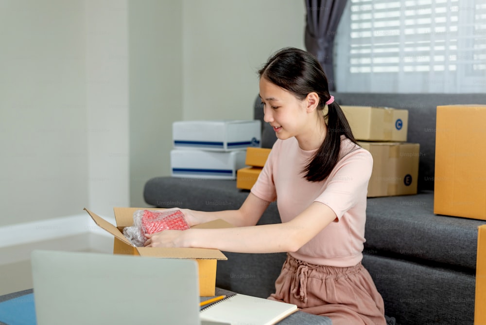 Young asian woman entrepreneur working packing the order for shipping to customer at house.