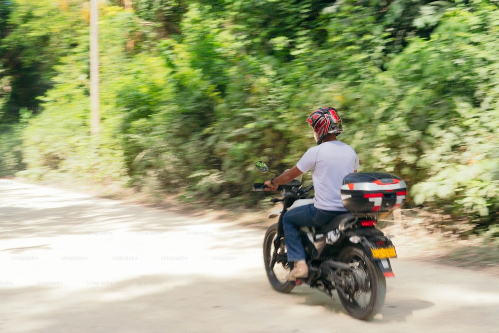 Hispanic Man with helmet, driving at high speed. Behind him is a blurred green background.