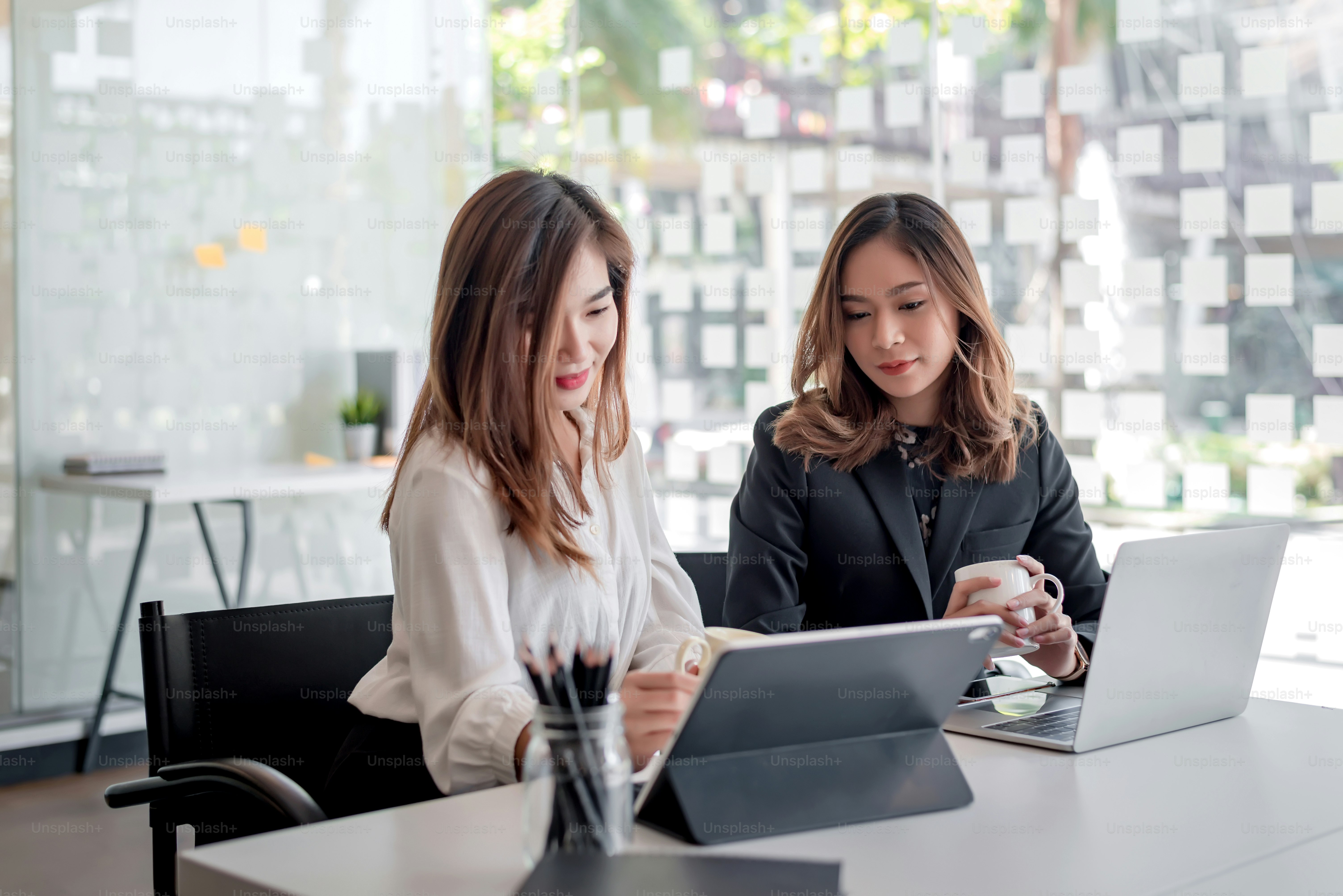 Deux jeunes femmes d’affaires asiatiques discutant et travaillant ...