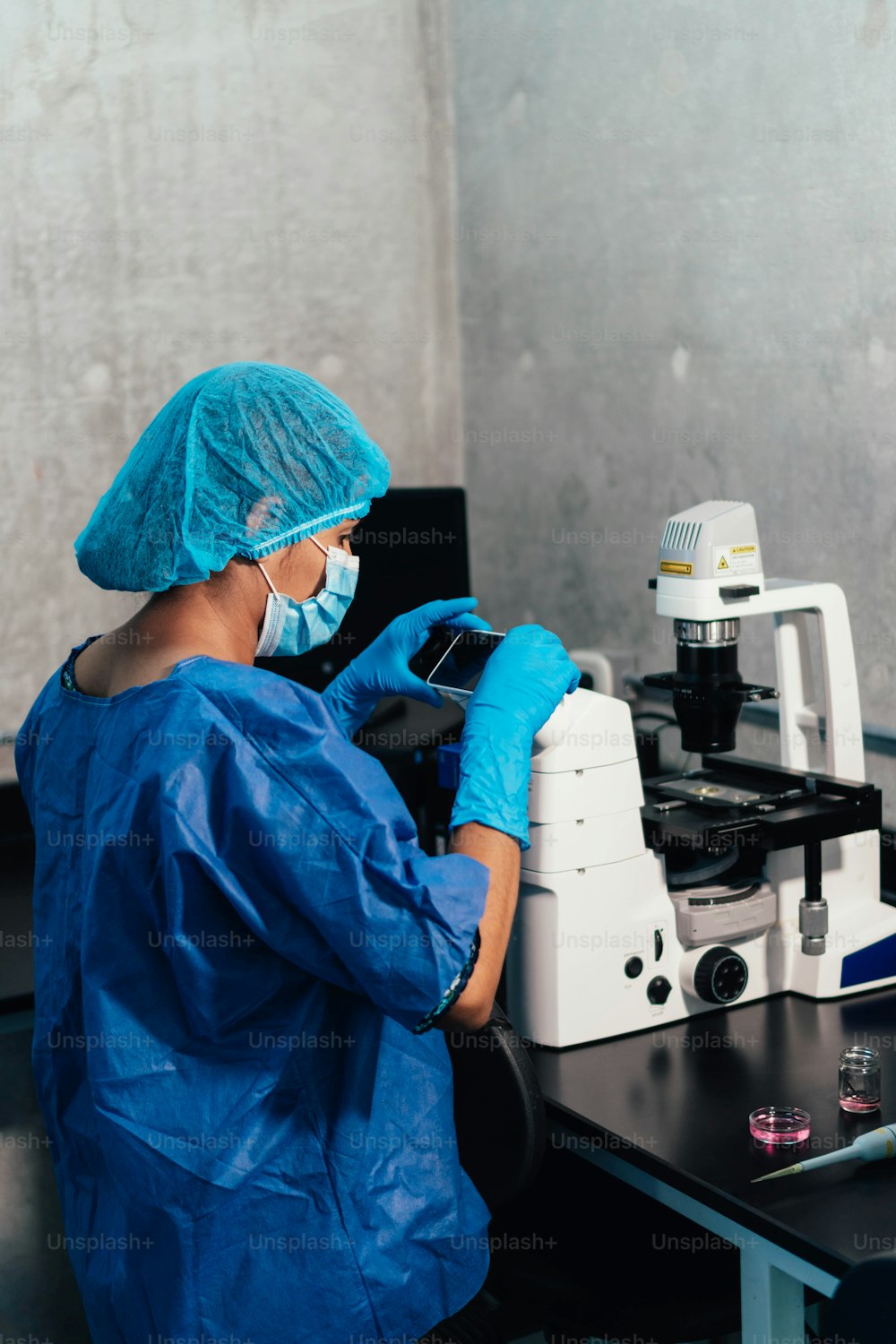 Woman working in a professional laboratory with cell phone and microscope