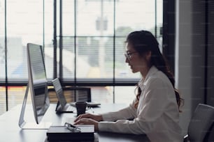 Giovane donna d'affari asiatica che digita la tastiera sul computer portatile in ufficio.