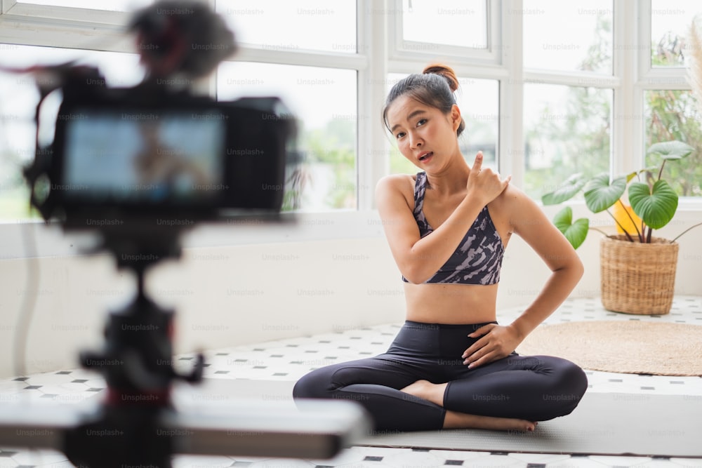 Asian woman trainer making online live streaming training and show how to exercise workout, yoga at home