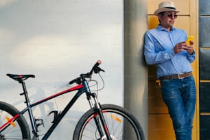 Businessman checking his cell phone next to his bicycle