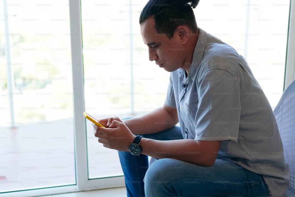 Man using cellular phone while sitting in living room