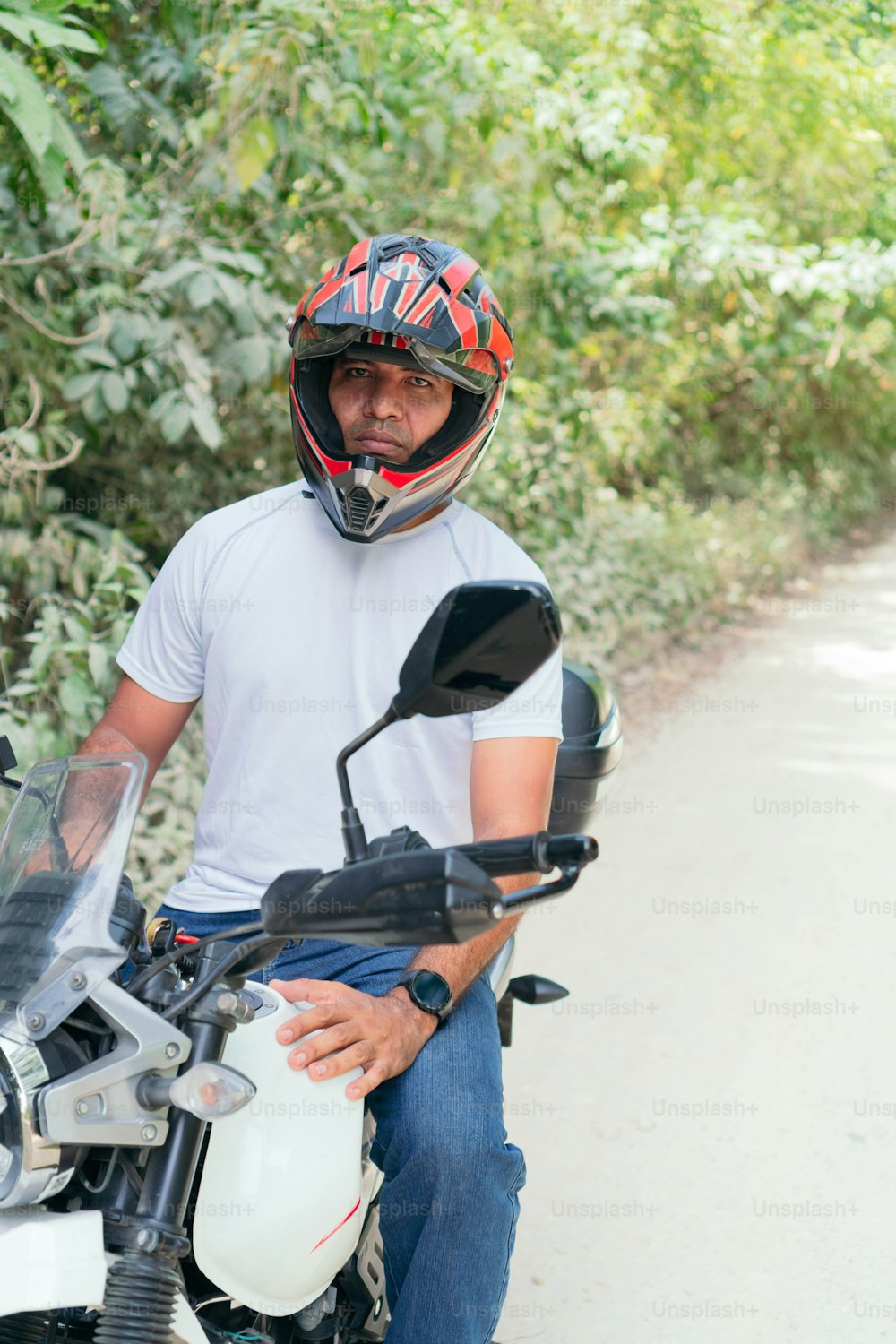 Hombre latino con su motocicleta estacionada en un camino rural
