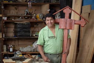 木の十字架をサンディングするポーズをとるメキシコの大工