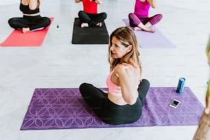Mexican mature woman sitting touching her shoulders while turning her back during yoga class in Latin America