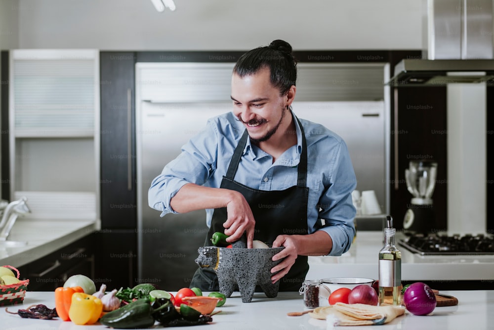 latin man cooking at home preparing salad or mexican sauce in kitchen at home in Mexico city