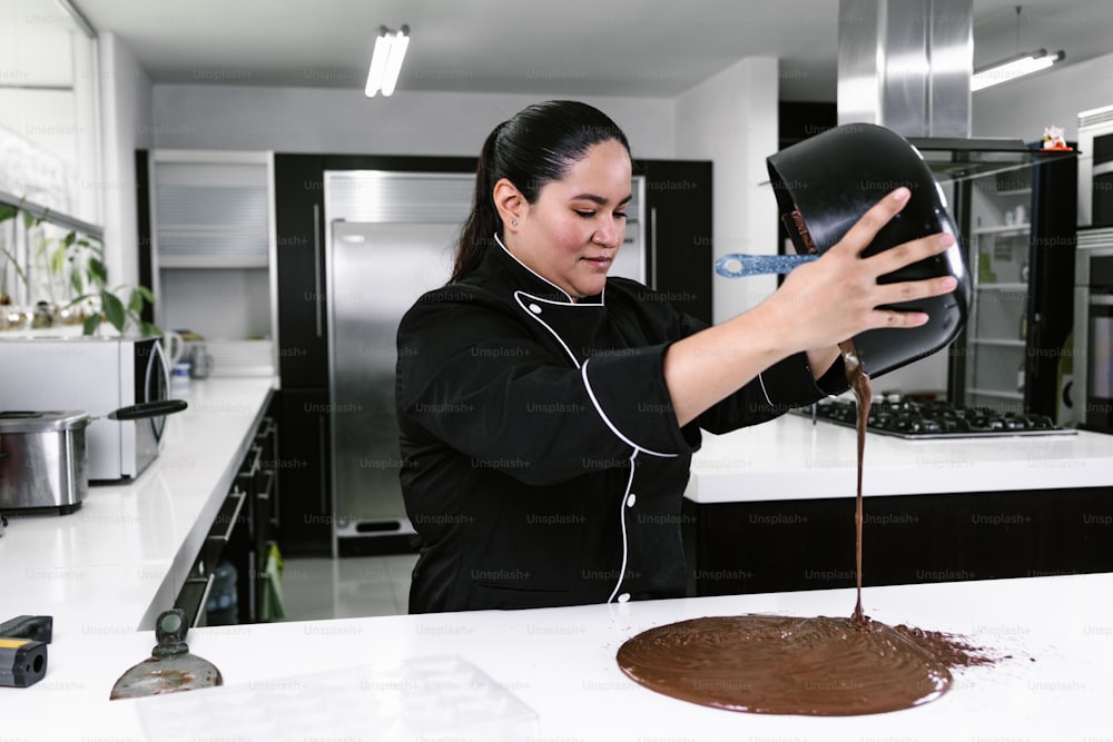 mulher latina chef confeiteiro vestindo uniforme preto no processo de preparação de deliciosos chocolates doces na cozinha no México América Latina
