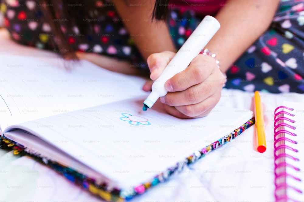Latin girl with down syndrome drawing in notebook, in disability concept in Latin America