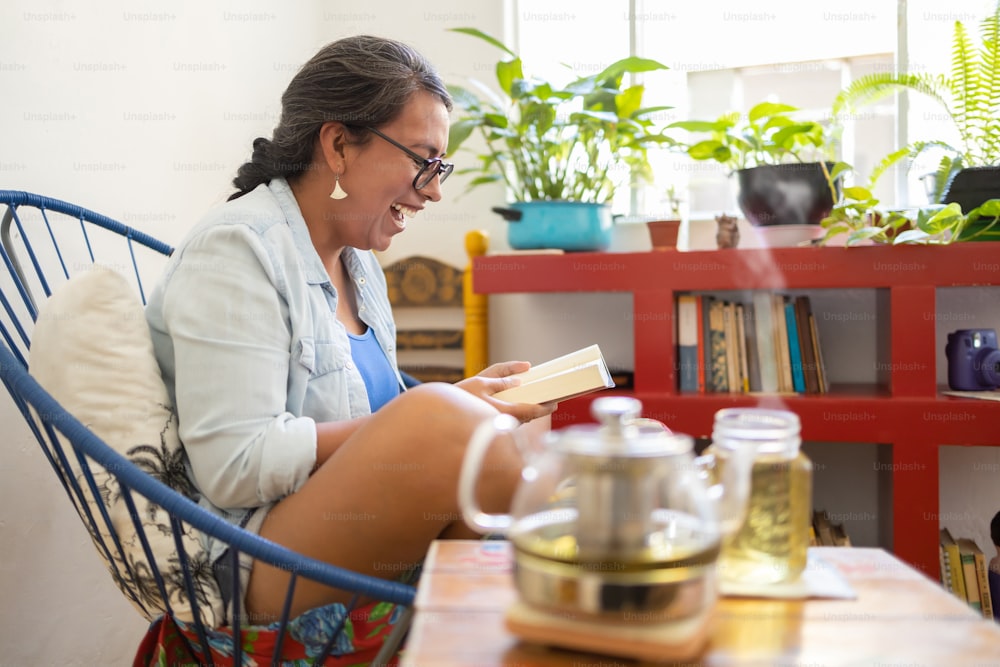 Mexikanische tätowierte Millennial-Frau, die ein Buch liest und lacht