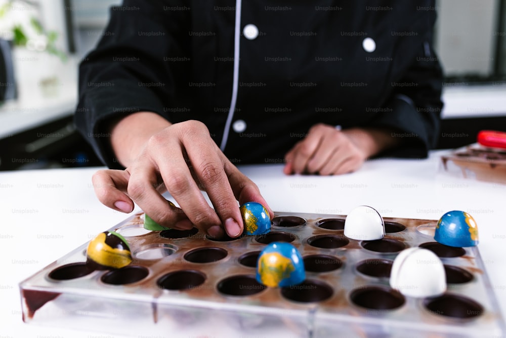 mão de mulher latina chef confeiteiro vestindo uniforme preto no processo de preparação de deliciosos chocolates doces na cozinha no México América Latina