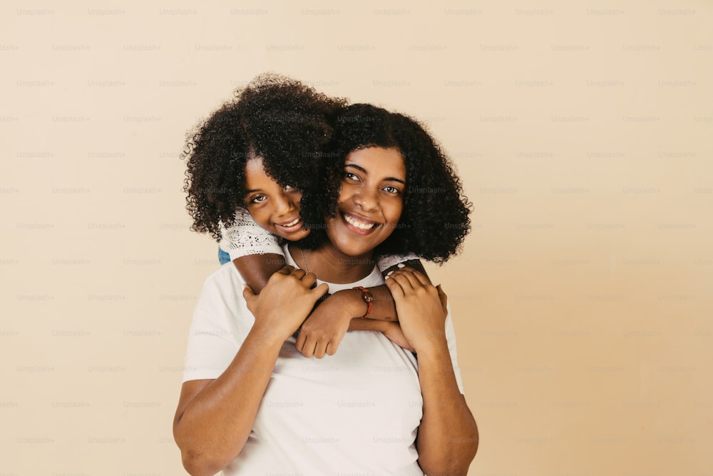 young black mother and little daughter hugging each other looking at camera