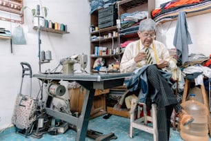Sastre mexicano envejecido cosiendo a mano en negocio local
