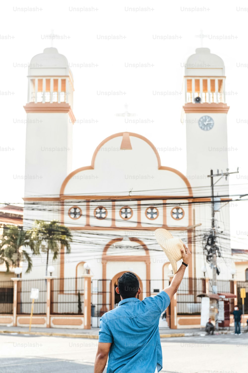 unrecognizable man hold a hat in front of the San Isidro church in the City of La Ceiba, Honduras.