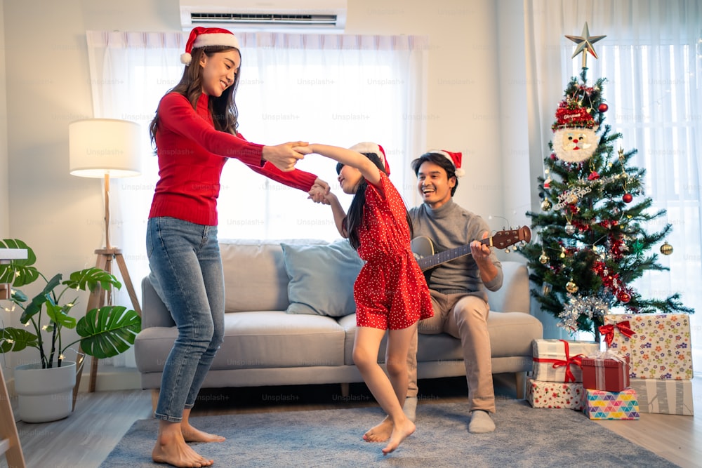 Asian lovely family member enjoy sing Christmas song together at home. Young little daughter feeling happy and excited to celebrate holiday Christmas Thankgiving party together with parents in house.