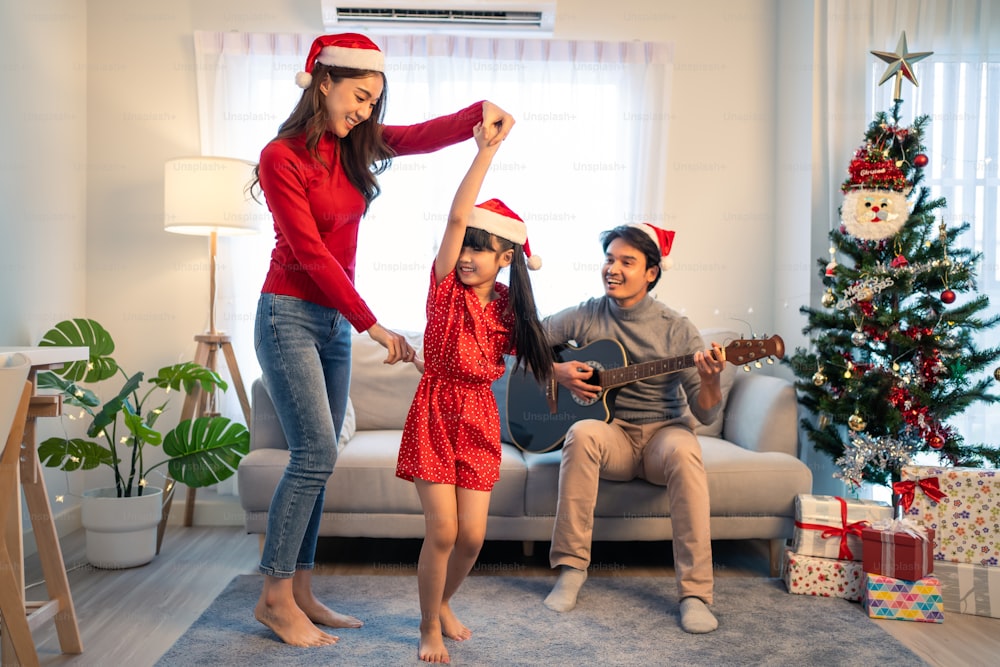 Asian lovely family member enjoy sing Christmas song together at home. Young little daughter feeling happy and excited to celebrate holiday Christmas Thankgiving party together with parents in house.