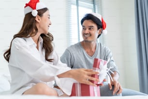 Asian beautiful young woman open xmas present gift box from boyfriend. Attractive girl feeling happy and excited for surprise from husband and ready to celebrate holiday Christmas together in house.