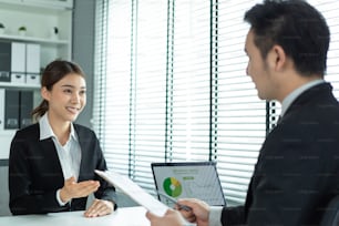 Asian beautiful woman talk with hr manager for job interview in office. Attractive female sit on table and give resume to human resources managers business recruit people for apply job at workplace.