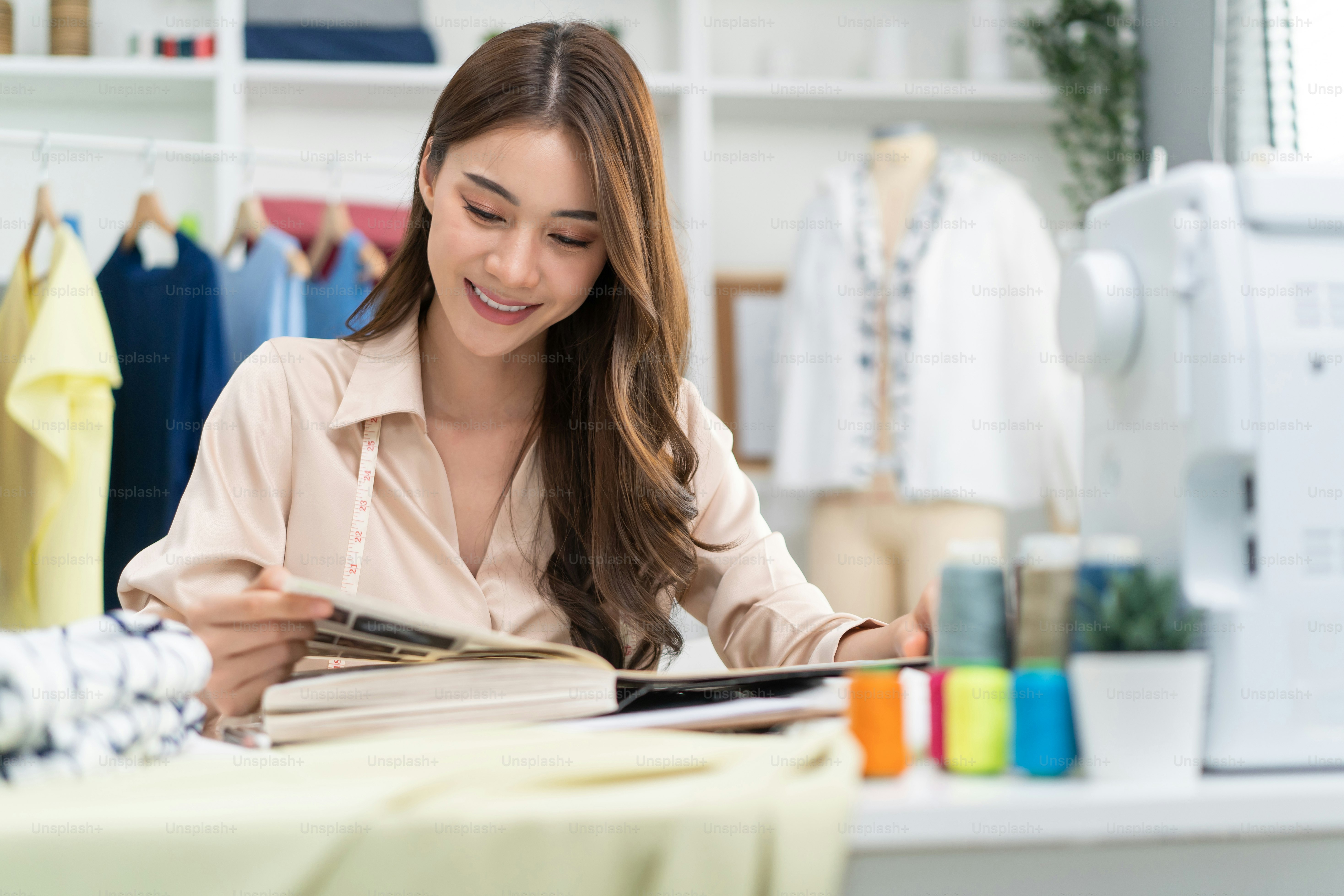 Asian tailor woman working to design new clothes in tailoring atelier.  Attractive young female fashion designer dressmaker create new pieces of  clothing from patterns and designs in workshop room. photo  Pattern