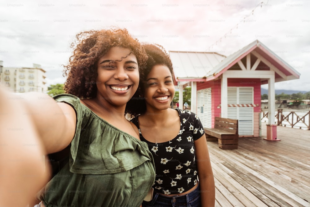 Happy african friends of tourist smiling and taking a selfie at the landmark in La Ceiba, Honduras.