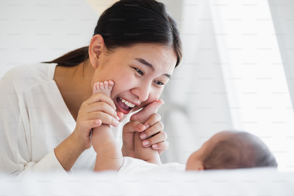 young Asian mother playing with her newborn baby feeling happy