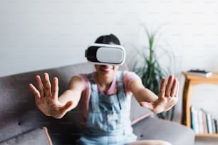 Young latin woman playing and using virtual reality glasses at home in Mexico Latin America