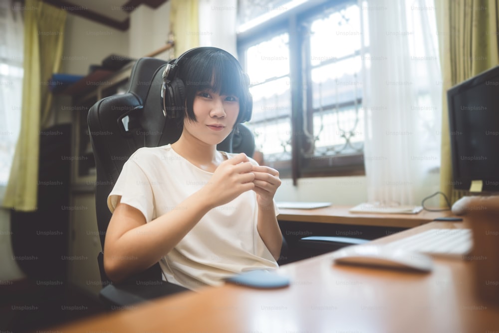 Jeune adulte femme asiatique rester à la maison concept. Elle porte des écouteurs. Entreprise de travail indépendant le jour sur le lieu de travail de la maison le jour.