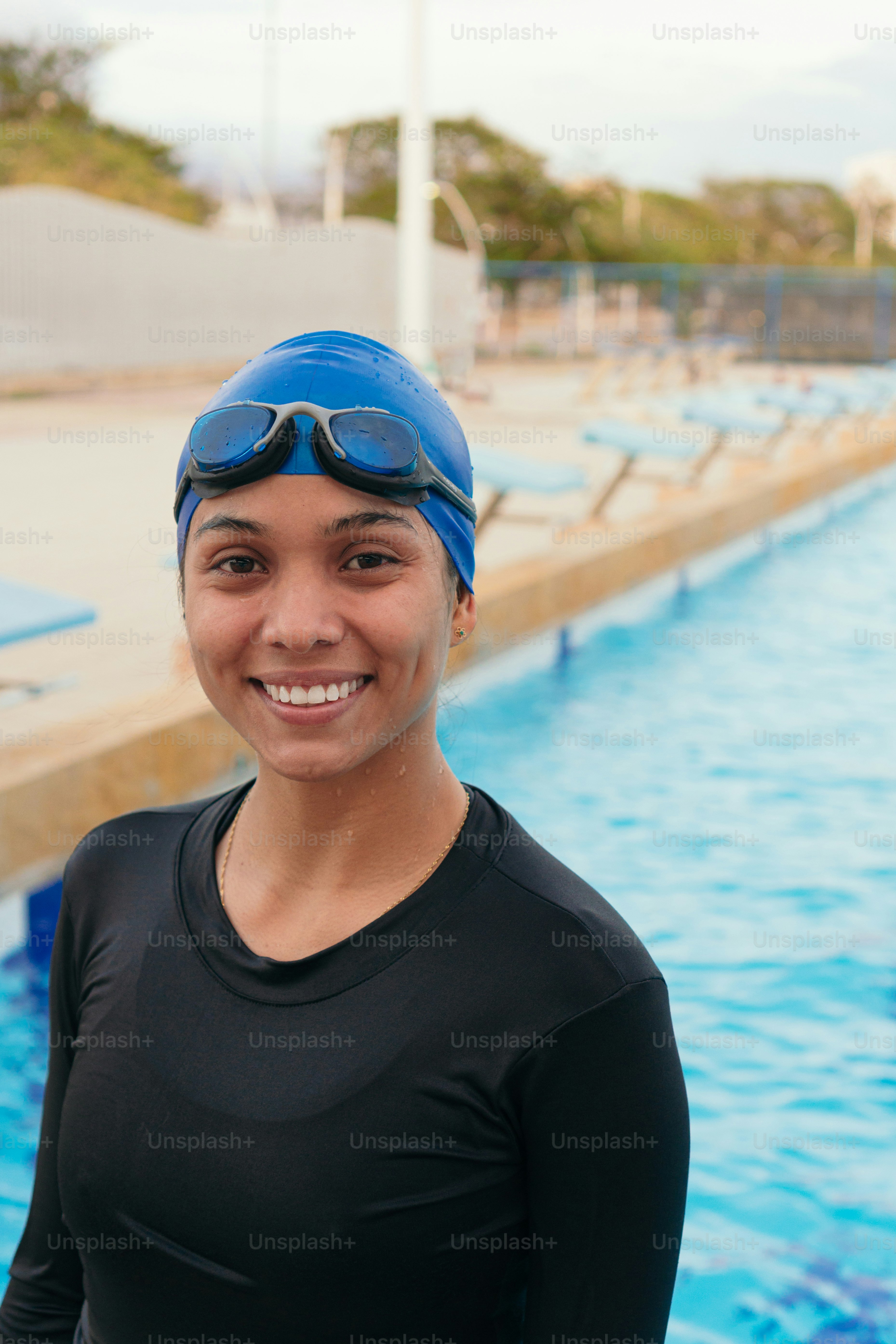 Female swimmer with googles and a cap posing outdoor