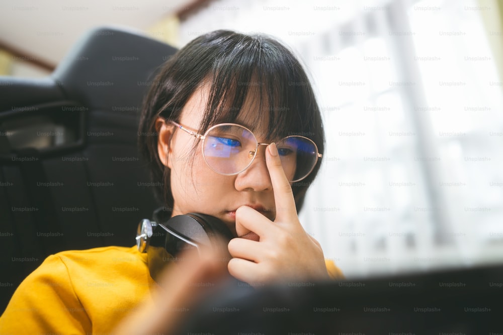 Mujer gamer asiática adulta joven estilo nerd usa anteojos jugar un juego en línea. Competencia por el estado de ánimo de la victoria. Estilo de vida de ocio de la gente en casa.