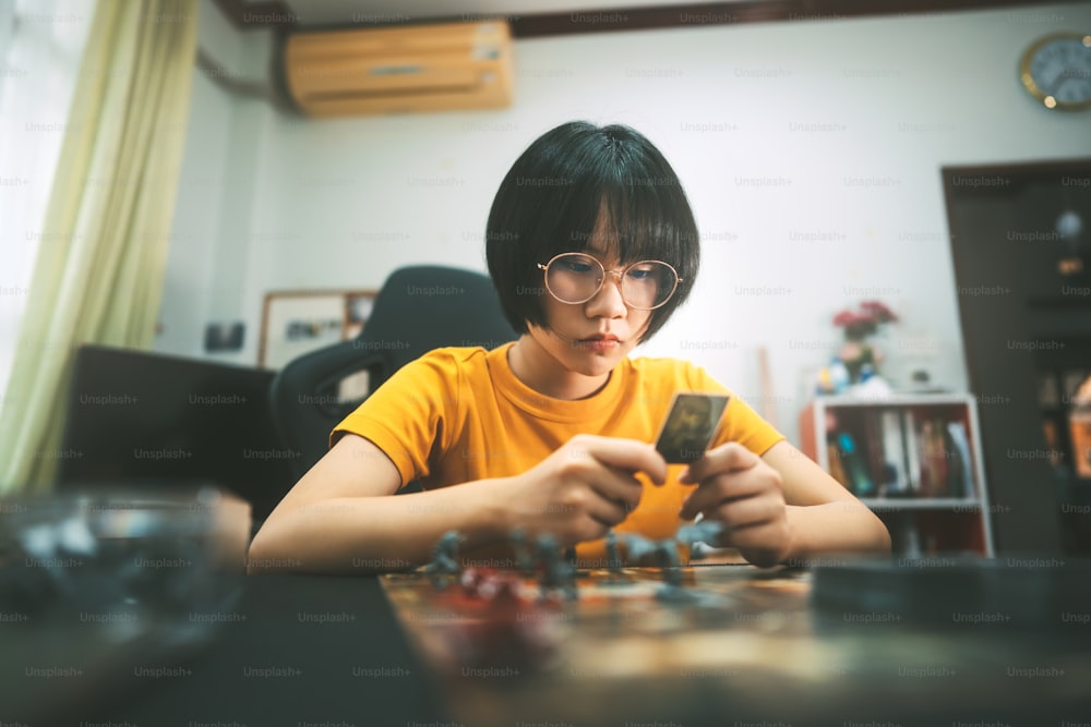 People lifestyle with interesting hobby at home concept. Young adult asian woman playing board game on top table. Happy with smile face and eye looking at camera.