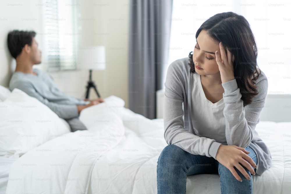 Asian young girl feel angry boyfriend having conflict domestic problem. New marriage man and woman feel heartbroken for quarrel conflict while sit on bed in bedroom. Family problem-separation concept.