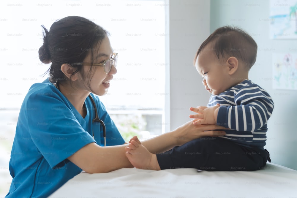 Happy Asian doctor or pediatrician checking baby patient at clinic