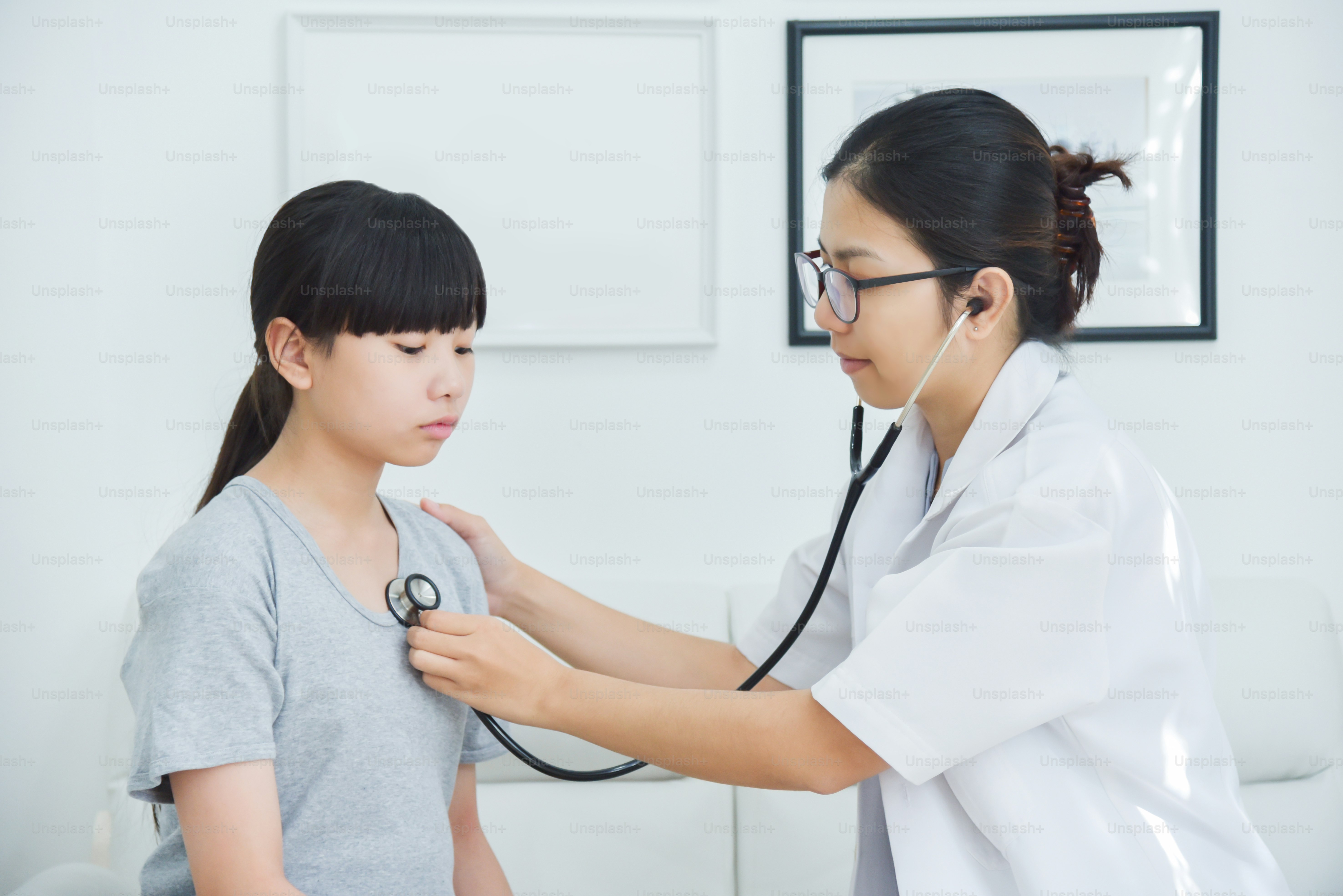 Young Asian Female Doctor examining a little girl with stethoscope. Medicine and health care concept.