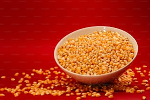 una ciotola bianca piena di chicchi di mais su sfondo rosso