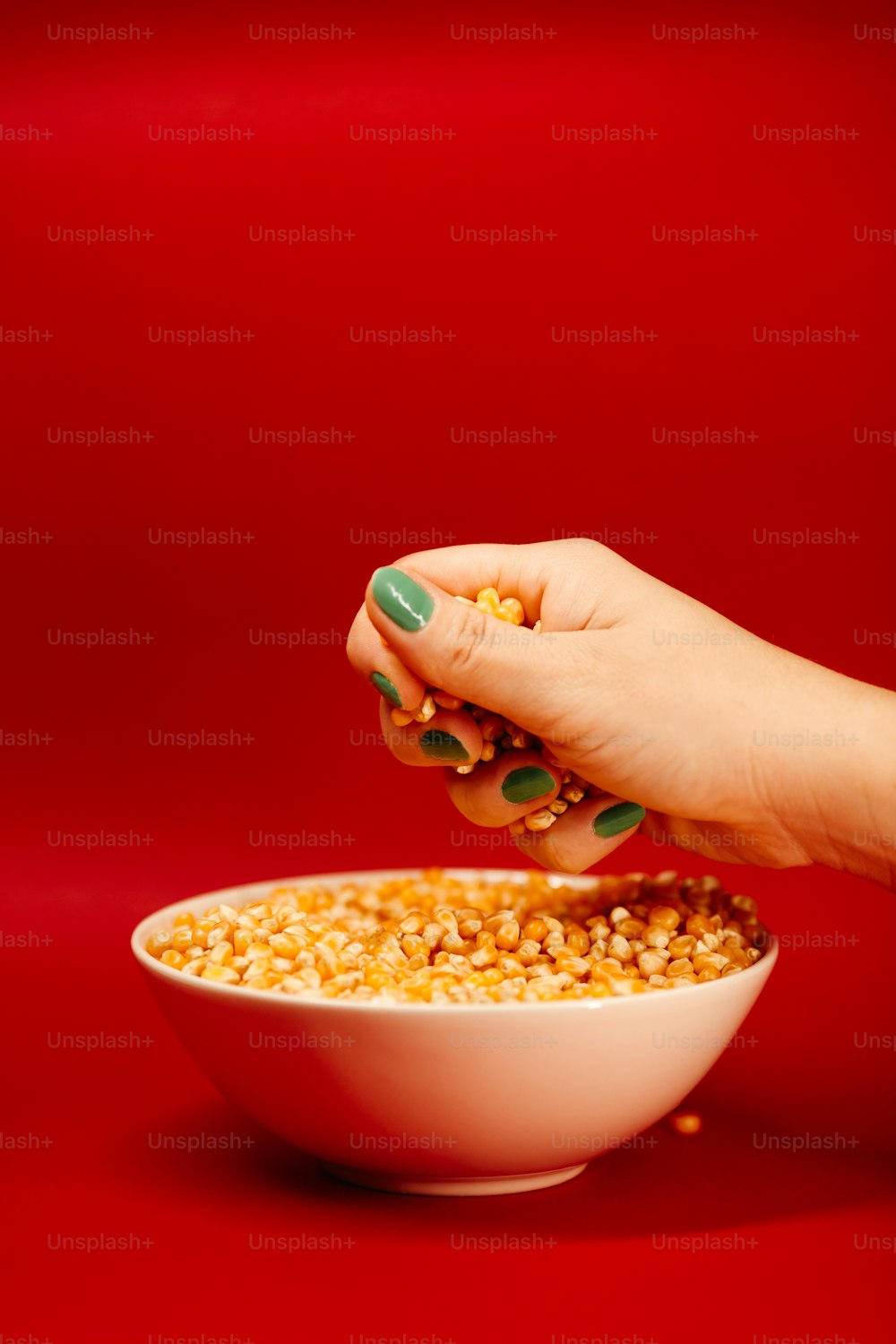 a woman's hand reaching into a bowl of corn