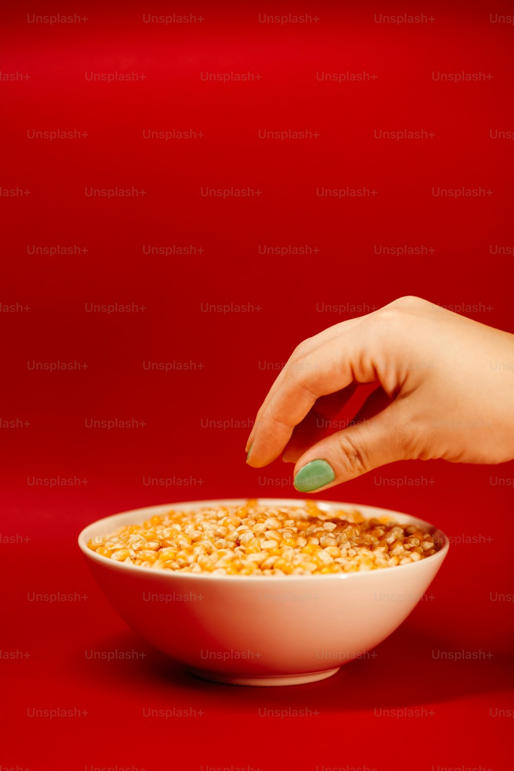 a woman's hand reaching into a bowl of corn