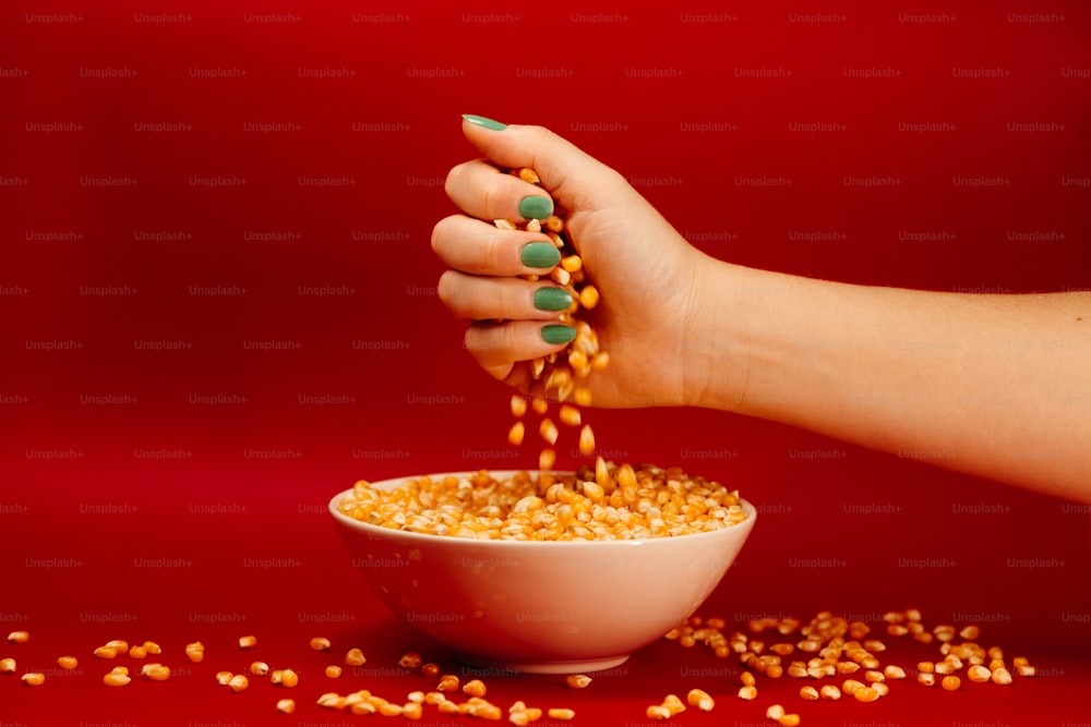 a woman's hand pouring corn into a bowl