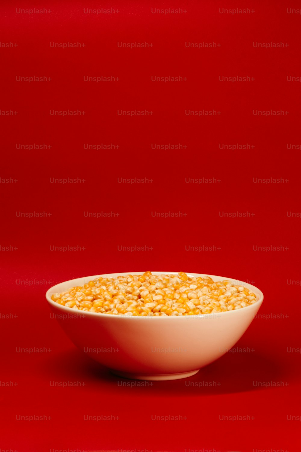 a bowl of corn on a red background