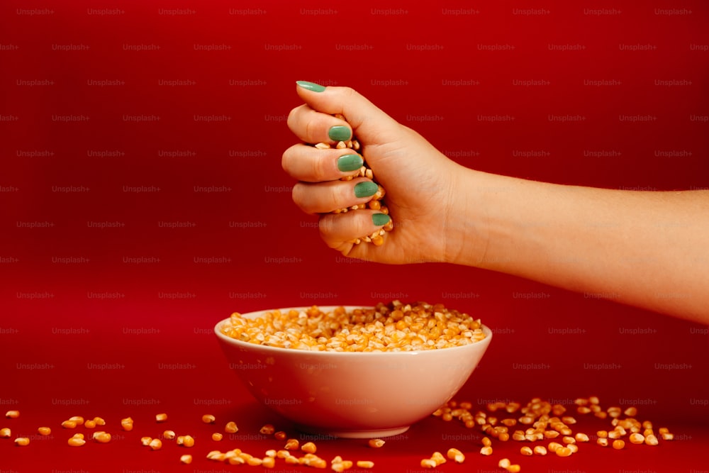 a woman's hand reaching into a bowl of corn