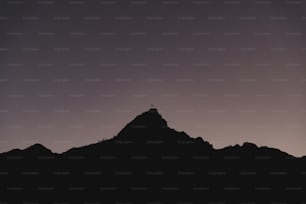 la silhouette d’une personne debout au sommet d’une montagne