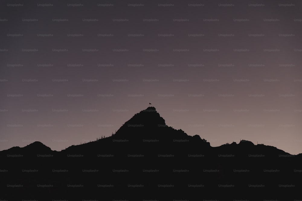 a silhouette of a person standing on top of a mountain