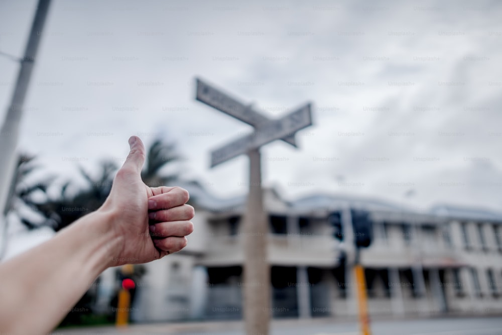 a person giving a thumbs up with a street sign in the background