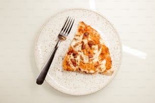 una fetta di pizza su un piatto con una forchetta