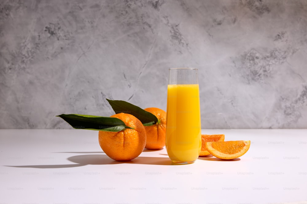 a glass of orange juice next to some oranges