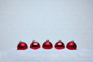 eine Gruppe roter Ornamente, die auf einem schneebedeckten Boden sitzen