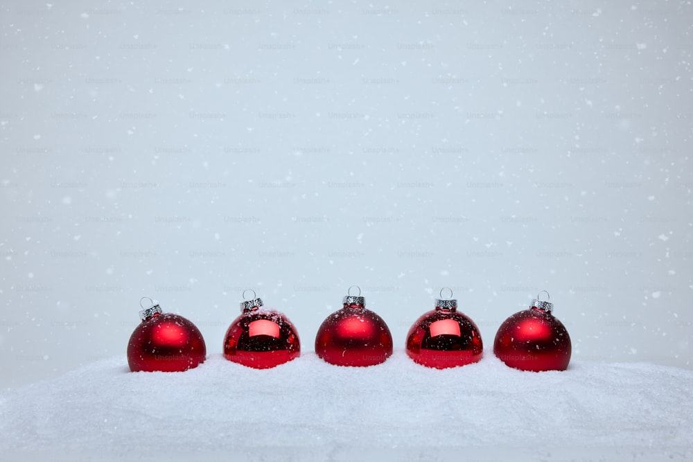 um grupo de ornamentos vermelhos sentados em cima de um chão coberto de neve