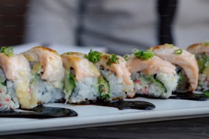 a white plate topped with sushi covered in sauce