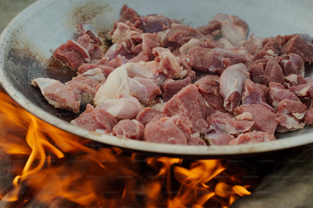 Una sartén llena de carne encima de un fuego